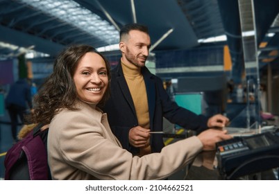 Beautiful Middle Aged Ethnic Couple - Woman Of Middle Eastern Descent And Handsome Caucasian Man Holding Out Passports While Going Through Passport And Customs Control At International Airport