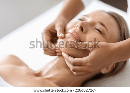 Beautiful Middle Aged Woman Getting Face Lifting Massage In Luxury Spa Salon, Masseur Making Double Chin Treatment Procedure To Relaxed Mature Female Lying With Eyes Closed, Closeup Portrait ストックフォト © 