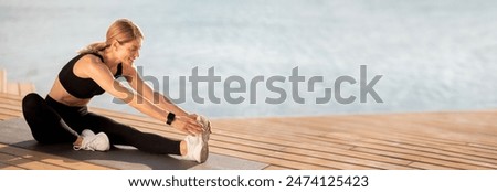 Beautiful Middle Aged Woman Stretching Legs While Training Outdoors On The Pier, Smiling Sporty Female Sitting On Yoga Mat Near Water And Doing Fitness Exercises, Touching Toes With Hands, Copy Space