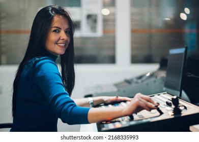 Beautiful Middle Aged Beautiful Woman Working On A Tv Station As A Producer In A Broadcast Control Room. Show Production Maker. Portrait Of A Woman Tv Station Worker Looking Into The Camera.