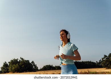 Beautiful Middle Aged Young Woman Running With Music Headphones Smiling. Healthy Life Style