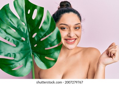 Beautiful middle eastern woman holding green plant leaf close to face screaming proud, celebrating victory and success very excited with raised arm  - Shutterstock ID 2007279767