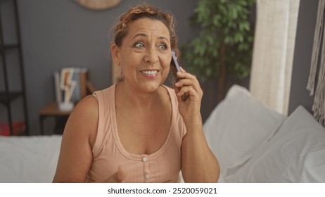 A beautiful middle-aged hispanic woman with curly hair talks on the phone while sitting in a cozy bedroom with a bed and indoor plants. - Powered by Shutterstock