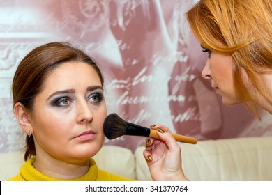 Beautiful middle-aged model, which is applied makeup. Makeup artist at work.
