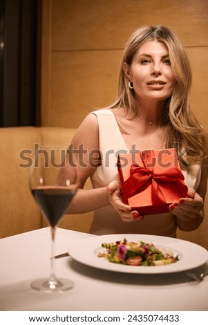Beautiful middle-aged woman holds gift box with bow in her hands