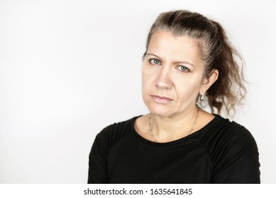 Beautiful middle-aged woman with a sad face on a light background, her hair begins to turn gray so she is not happy, it is time to dye her hair. Beauty concept