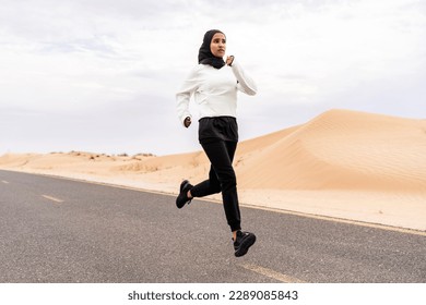 Beautiful middle-eastern arab woman wearing hijab training outdoors in a desert area - Sportive athletic muslim adult female wearing burkini sportswear doing fitness workout - Powered by Shutterstock