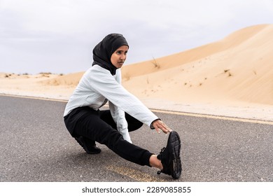 Beautiful middle-eastern arab woman wearing hijab training outdoors in a desert area - Sportive athletic muslim adult female wearing burkini sportswear doing fitness workout - Powered by Shutterstock