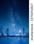 Beautiful milky way and pallas mountains at moonlight with long shadows of the spruce trees and fresh snow in Pallas-Yllästunturi National Park in Muonio, Finland