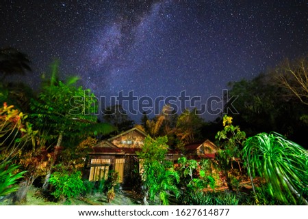 Beautiful milky way stars in the night sky over the jungle forest with cabins in North Sulawesi, Indonesia