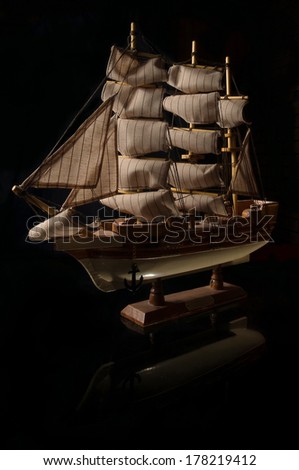 Beautiful miniature ship. Wooden ship figurine. Antique model sailing ship isolated with clipping path. Model of ship with sails on black background