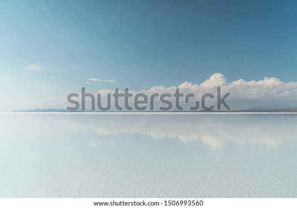 Beautiful mirror reflection on blue sky and cloud on\
Bolivia\'s Salt Flats. Shot in Salar de Uyuni salt flat. Water\
reflection of clouds and empty space. Holiday, vacation, freedom\
scene with horizon. 