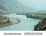 Beautiful misty mountain landscape with wide mountain river. Dark green gloomy scenery with big mountain river in mist. Dark atmospheric view to great river among big mountains in rainy weather.