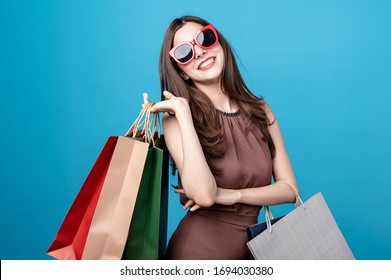 Beautiful Mix Race Caucasian Asian Woman Are Holding Shopping Bags With Face Happily In Blue Seamless,isolated Background. Shopping Lifestyle, Online Shopping, Promotion Presenter Concept.
