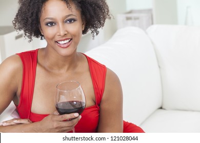 A Beautiful Mixed Race African American Girl Or Young Woman Wearing A Red Dress Looking Happy And Drinking Red Wine