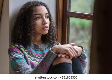 Beautiful mixed race biracial African American girl teenager female young woman sad depressed or thoughtful looking out of a window - Shutterstock ID 551803330