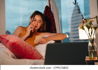 Beautiful Mixed Race Woman Enjoy Eating Bread For Snack And Watching Series On Laptop.