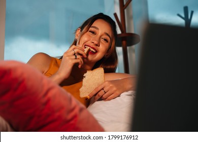 Beautiful Mixed Race Woman Enjoy Eating Bread For Snack And Watching Series On Laptop.