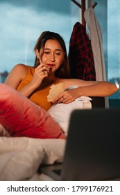 Beautiful Mixed Race Woman Enjoy Eating Bread For Snack And Watching Series On Laptop.