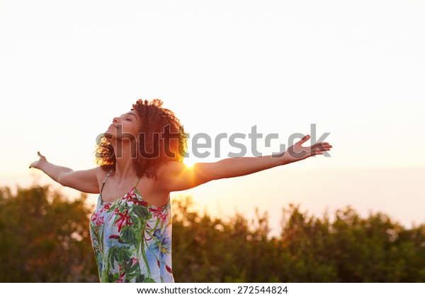 Beautiful mixed race woman expressing\
freedom outdoors with her arms\
outstretched