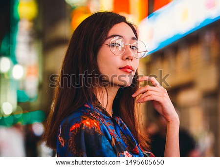 Beautiful mixed race woman posing outdoors, background with blurred neon lights