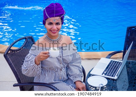 Beautiful mixed race woman remote working in the coffee shop summer cafe . indian female holding cup of tea . coffeebreak concept
