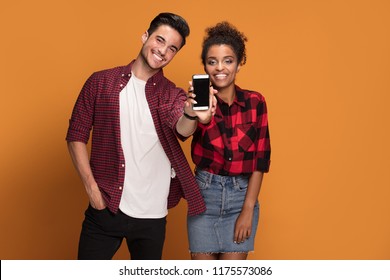 Beautiful mixed race young couple in casual clothes using smart phone in studio.