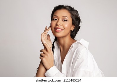 Beautiful mixed race young girl touch face enjoy perfect healthy smooth face skin, natural makeup. Pretty biracial female with ideal make-up posing on gray background. Skincare beauty cosmetics ad. - Powered by Shutterstock