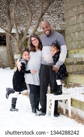 A Beautiful Mixed-race Family (African American And Filipino/Caucasian) Hugs Closely Together Posing Outside In Winter. Their Natural Joyful Expressions And Smiles Radiate Love. Rural Farm Background.