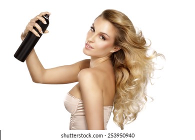 beautiful model applying spray  on windy hair on white