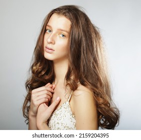 Beautiful model female with long wavy and shiny hair . Blond woman wearing white dress with curly hairsty