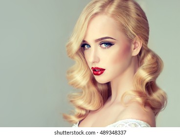 Beautiful model girl blonde  with long curled hair and  red lips . Hairstyle Hollywood wave