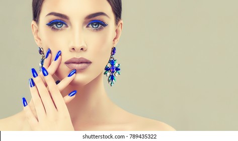 Beautiful model girl with blue  manicure on nails . Fashion makeup and cosmetics . Large earrings  jewelry .
