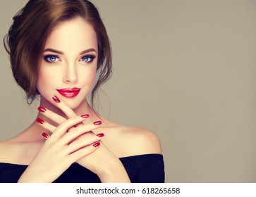 Beautiful model girl with elegant hairstyle . Woman with red lips and nails  . Cosmetics, beauty and manicure on nails