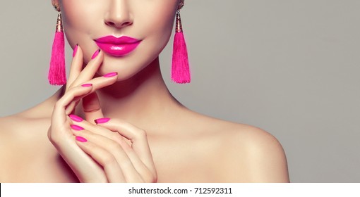 Beautiful model girl with pink fuchsia manicure on nails . Fashion makeup and cosmetics . Large earrings tassels jewelry Magenta color .