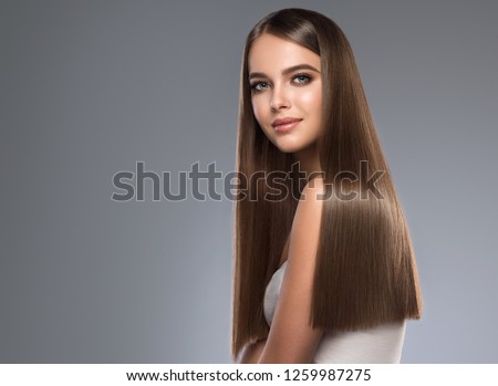 Beautiful model girl with shiny brown and straight long hair. Keratin  straightening. Treatment, care and spa procedures. Smooth hairstyle