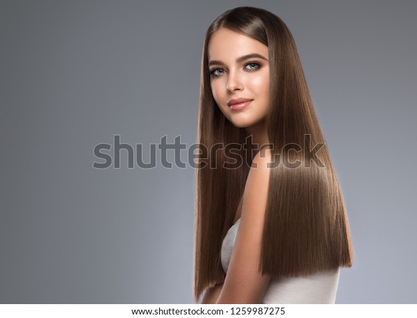 Beautiful model girl with shiny brown and\
straight long hair. Keratin  straightening. Treatment, care and spa\
procedures. Smooth\
hairstyle