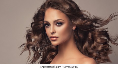 Beautiful model girl with wavy and shiny hair . Brunette woman with curly hairstyle