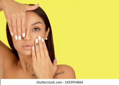 Beautiful model girl, woman with a white manicure nail design isolated on yellow background. Fashion natural makeup and care for hands and nails and cosmetics.