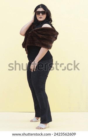 a beautiful model posing with brown fur stole and black top and glasses high heels 