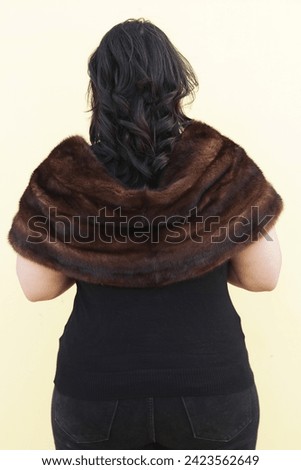 a beautiful model posing with brown fur stole and black top and glasses high heels 