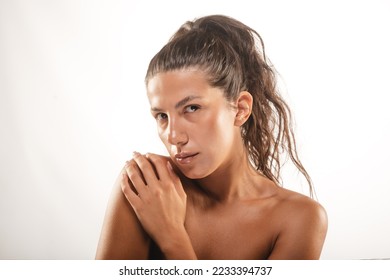Beautiful model posing while touching her shoulder at the studio on a white backround