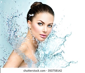 Beautiful Model Spa Woman with splashes of water. Beautiful Smiling girl under splash of water with fresh skin over blue background. Skin care, Cleansing and moisturizing concept. Beauty face