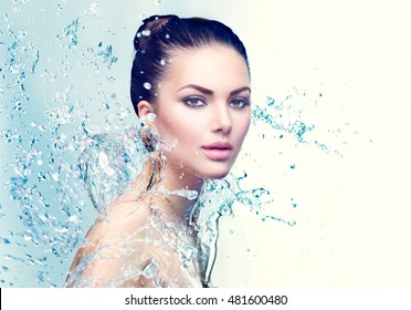 Beautiful Model Spa Woman with splashes of water. Beautiful Smiling girl under splash of water with fresh skin over blue background. Skin care, Cleansing and moisturizing concept. Beauty face