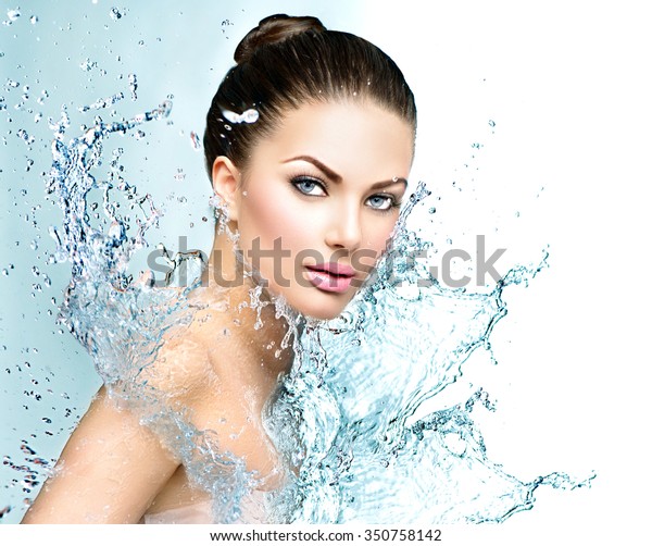Beautiful Model Spa Woman with splashes of water.\
Beautiful Smiling girl under splash of water with fresh skin over\
blue background. Skin care, Cleansing and moisturizing concept.\
Beauty face