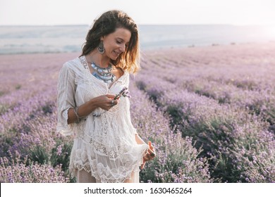 Beautiful model walking in spring or summer lavender field in sunrise sunshine. Boho style clothing and silver jewelry.