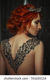 Beautiful model wearing creative body art dress is posing in a dark studio