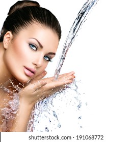 Beautiful Model Woman with splashes of water in her hands. Beautiful Smiling girl under splash of water with fresh skin over blue background. Skin care, Cleansing and moisturizing concept. Beauty face