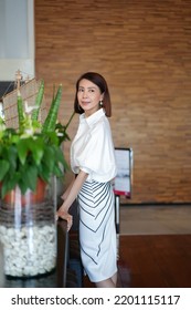 Beautiful Model Woman In White Dress In Modern Corporate Building Lobby.