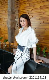 Beautiful Model Woman In White Dress In Modern Corporate Building Lobby.